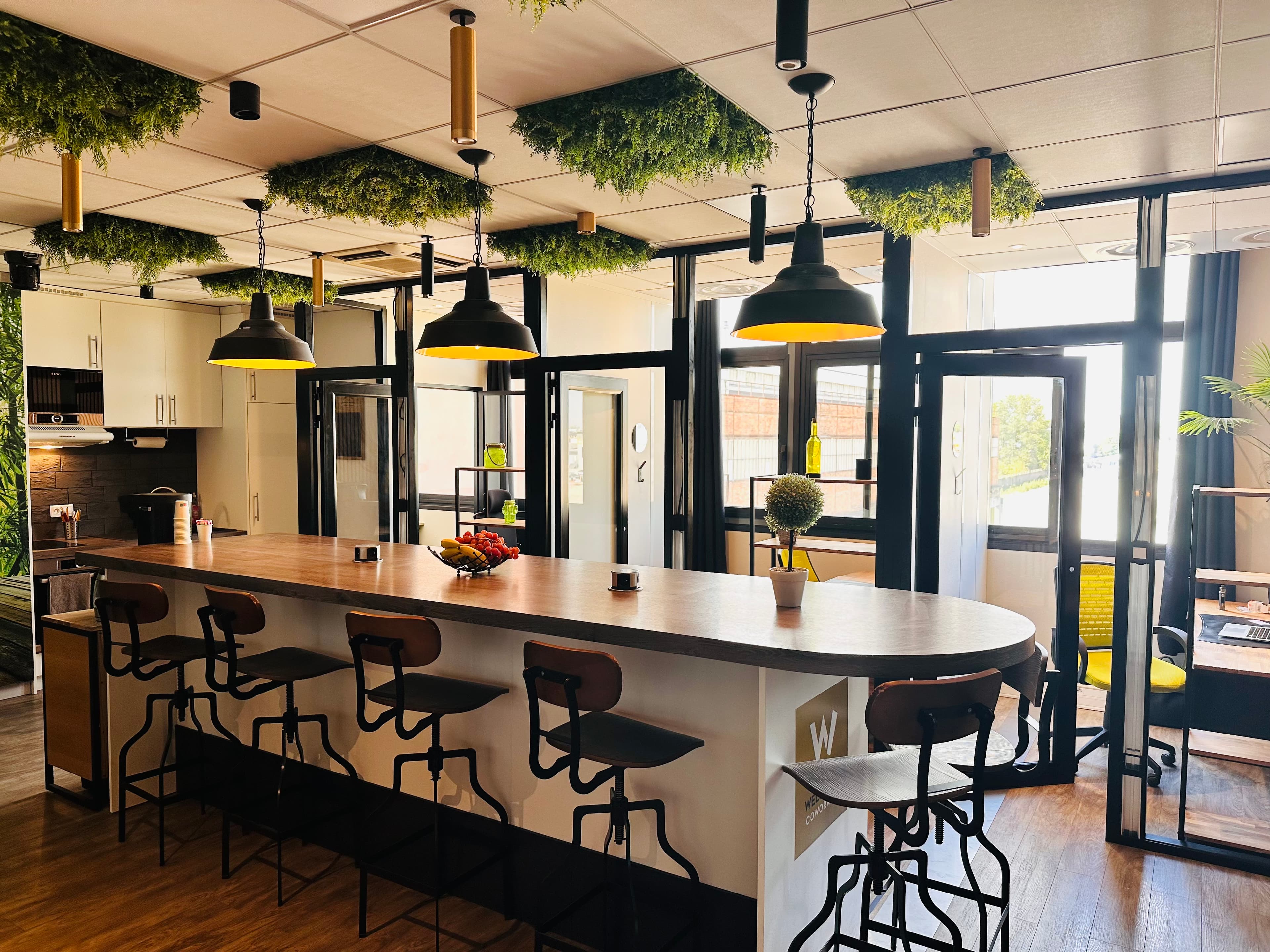 Gemeinschaftsbereich von Welcome Coworking und abgeschlossene Büros hinter Glaswänden
